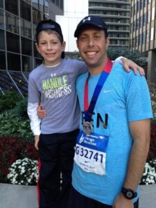 Proper Title's Ben Niernberg celebrates with his son after completing the Chicago Marathon one year after completing cancer treatment.