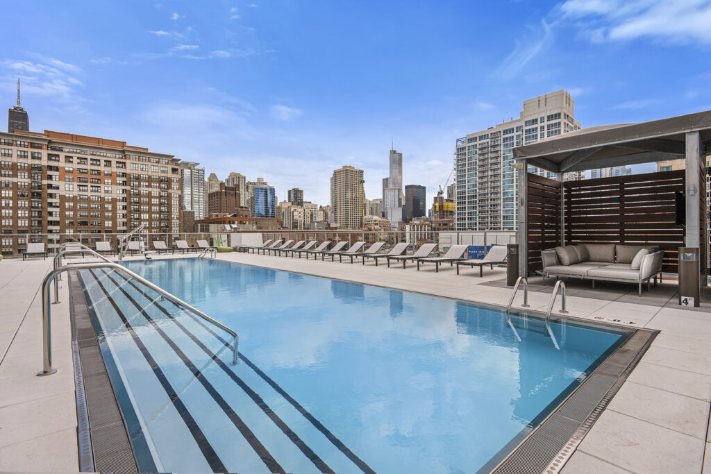 The sun terrace at NEXT Apartments in Chicago, featuring an outdoor pool, cabanas, spa, fire pit, grilling kitchens with seating areas and city views, is open now through Labor Day.